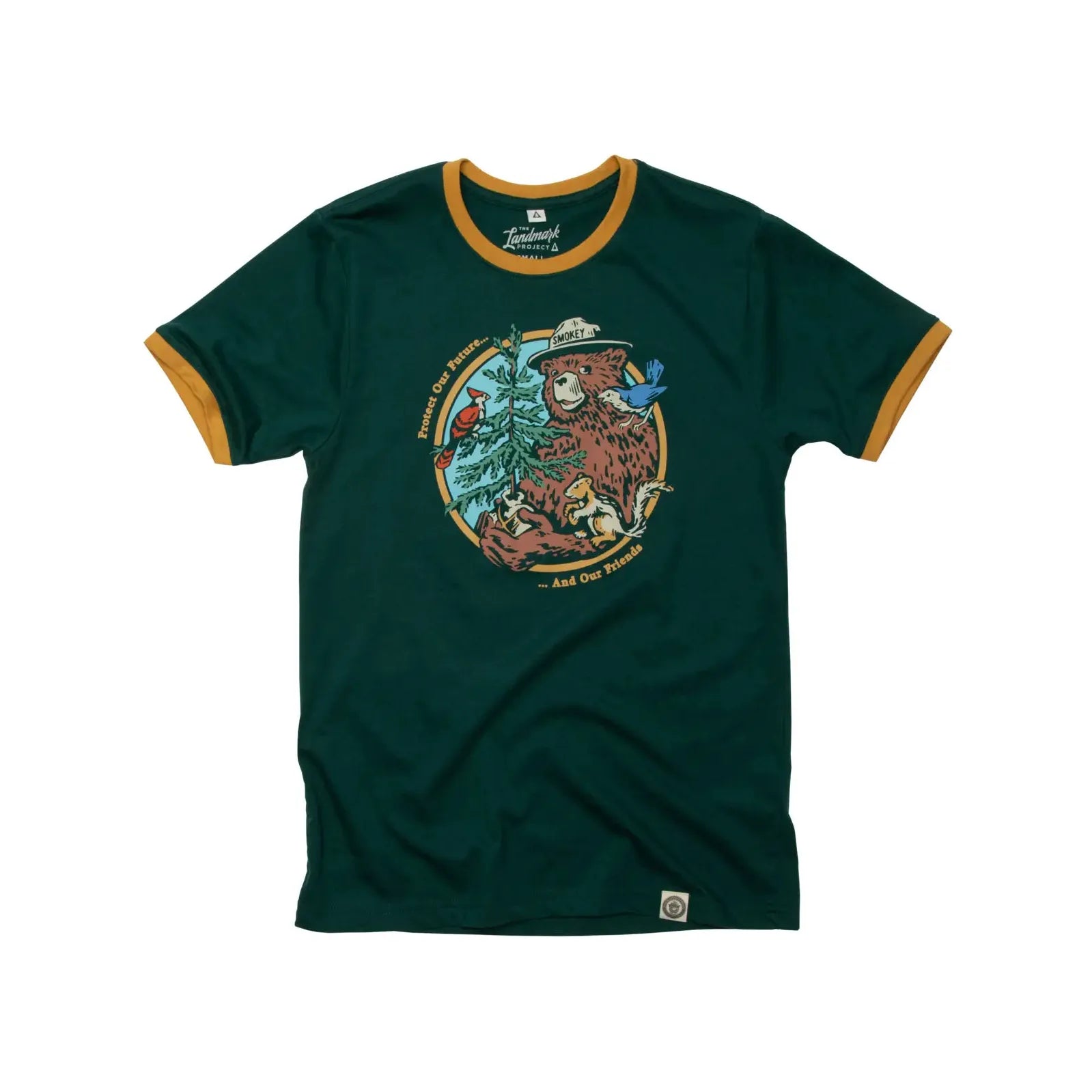 The Landmark Project Ringer Smokey Bear T-Shirt in Spruce showcases a green retro style with yellow trim, featuring an illustration of Smokey Bear wearing a hat, surrounded by trees and animals, and accompanied by text.