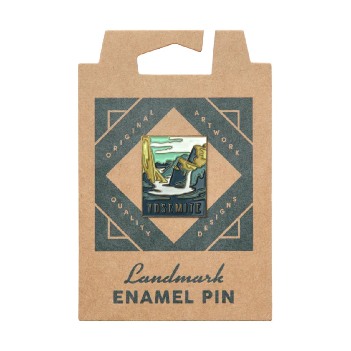 The Landmark Project Yosemite National Park Pin features a design of mountains and trees, attached to a brown cardboard backing labeled "Landmark Enamel Pin." It comes in sustainable packaging, providing a plastic-free experience for nature enthusiasts.